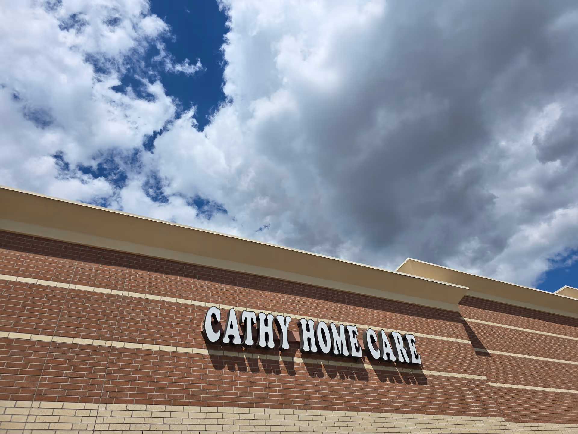 Exterior view of a brick facility with a large Cathy Home Care sign on the wall.