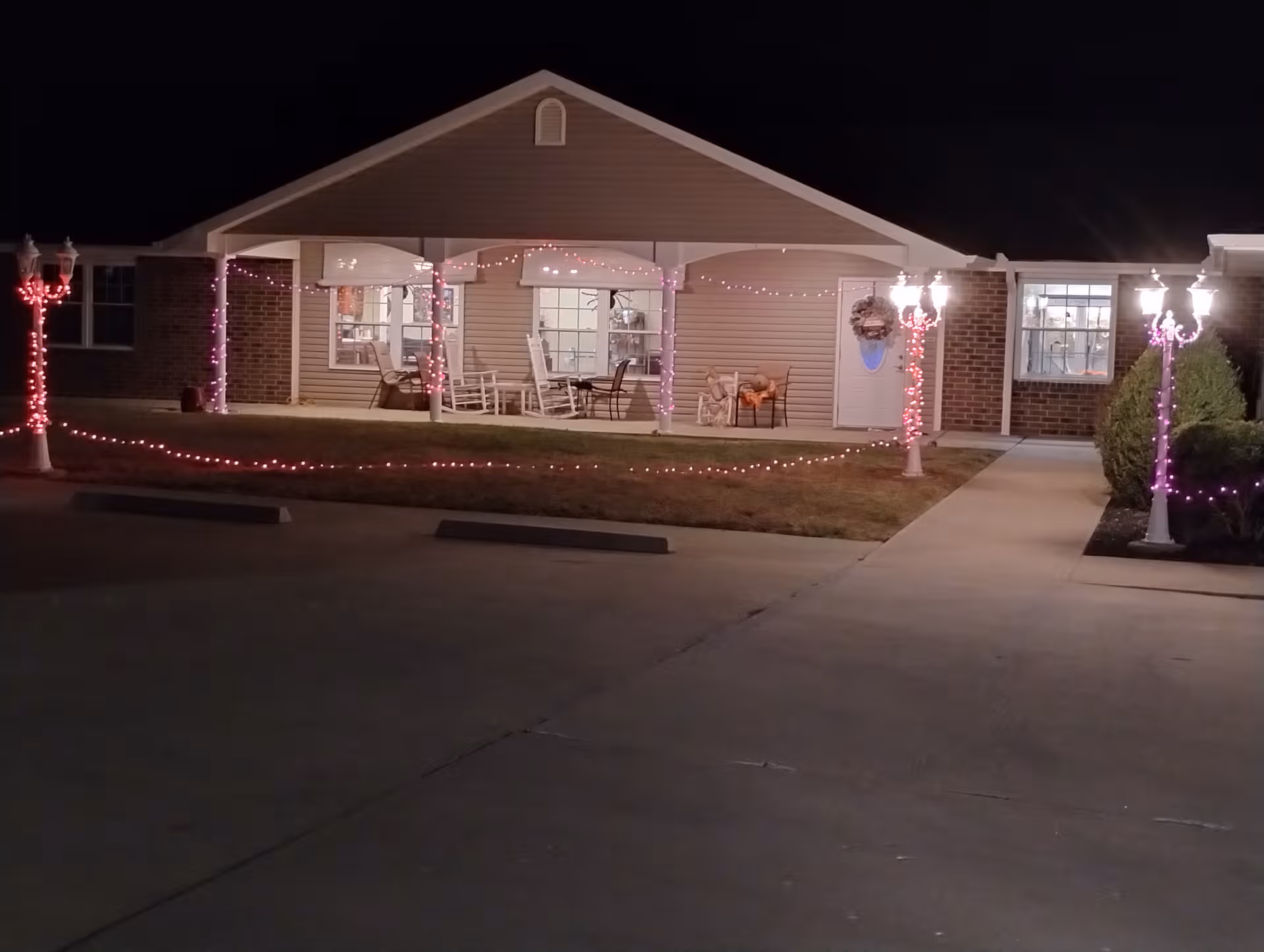 Night exterior of a senior living facility with a lit porch and string lights.