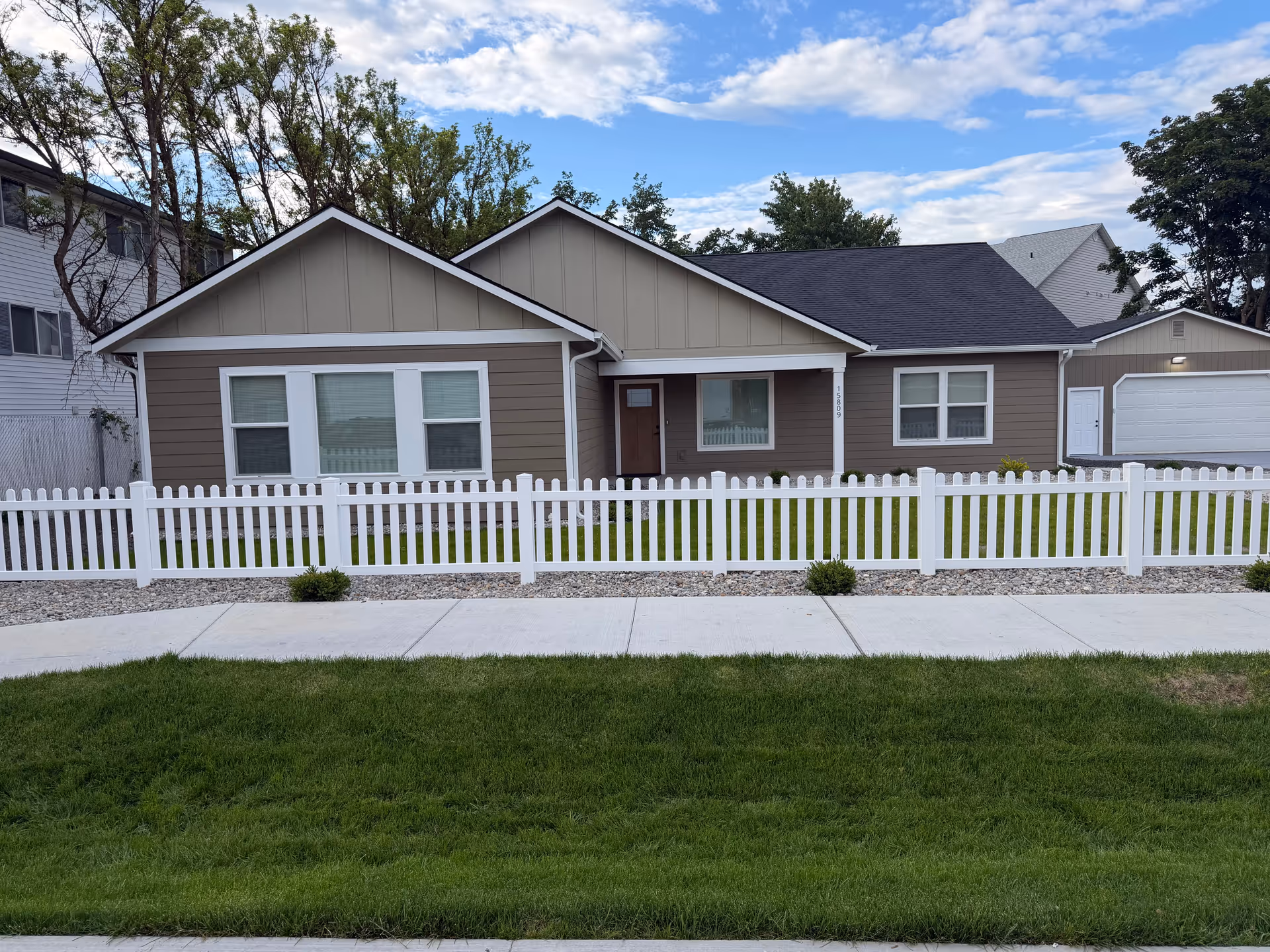 Single-story senior living facility front with white picket fence and well-kept lawn.