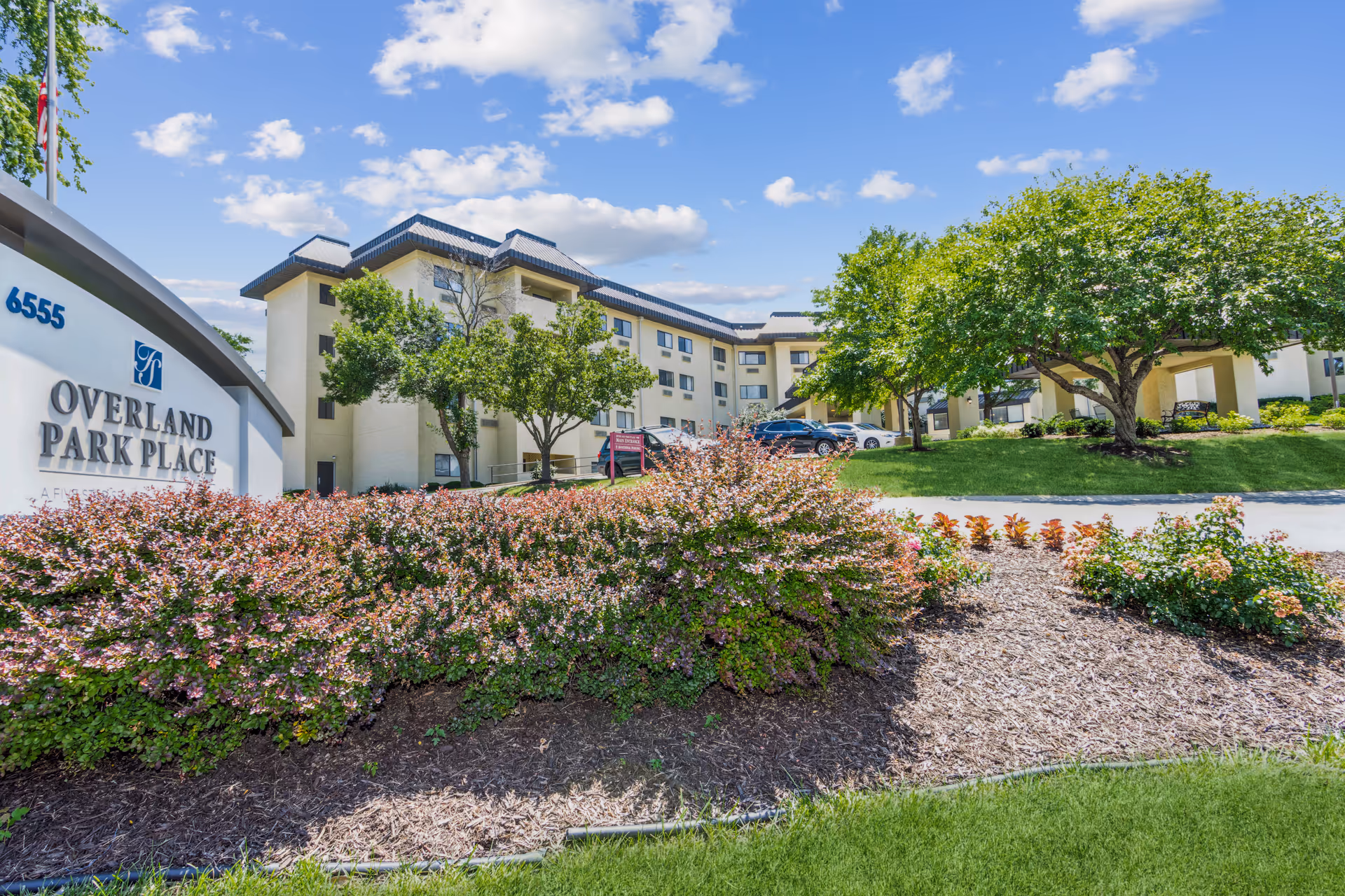 Exterior view of Overland Park Place senior living with sign, building, and landscaped grounds.
