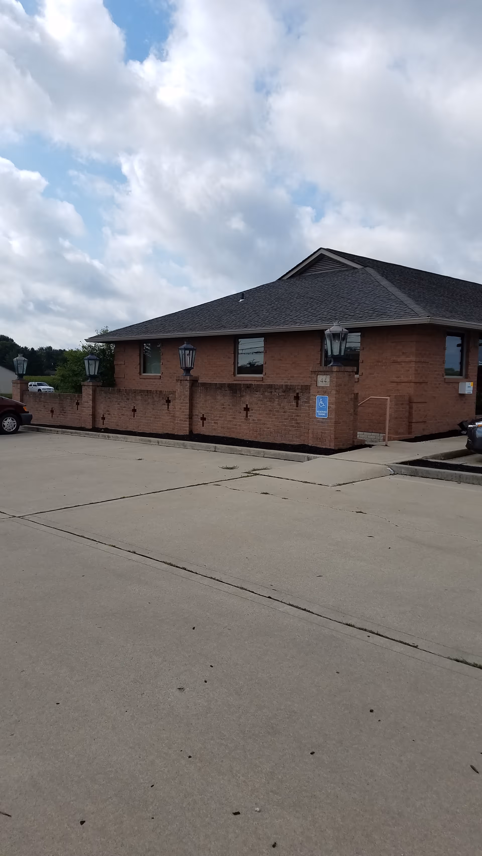 Brick senior care facility exterior with parking lot and handicap ramp.