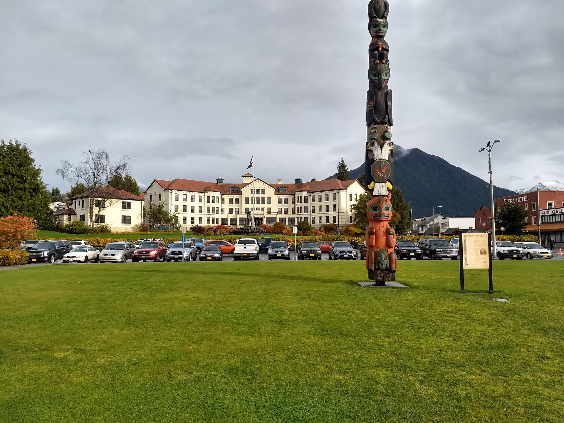 Exterior view of Pioneers' Home Sitka with a tall totem pole and line of parked cars.