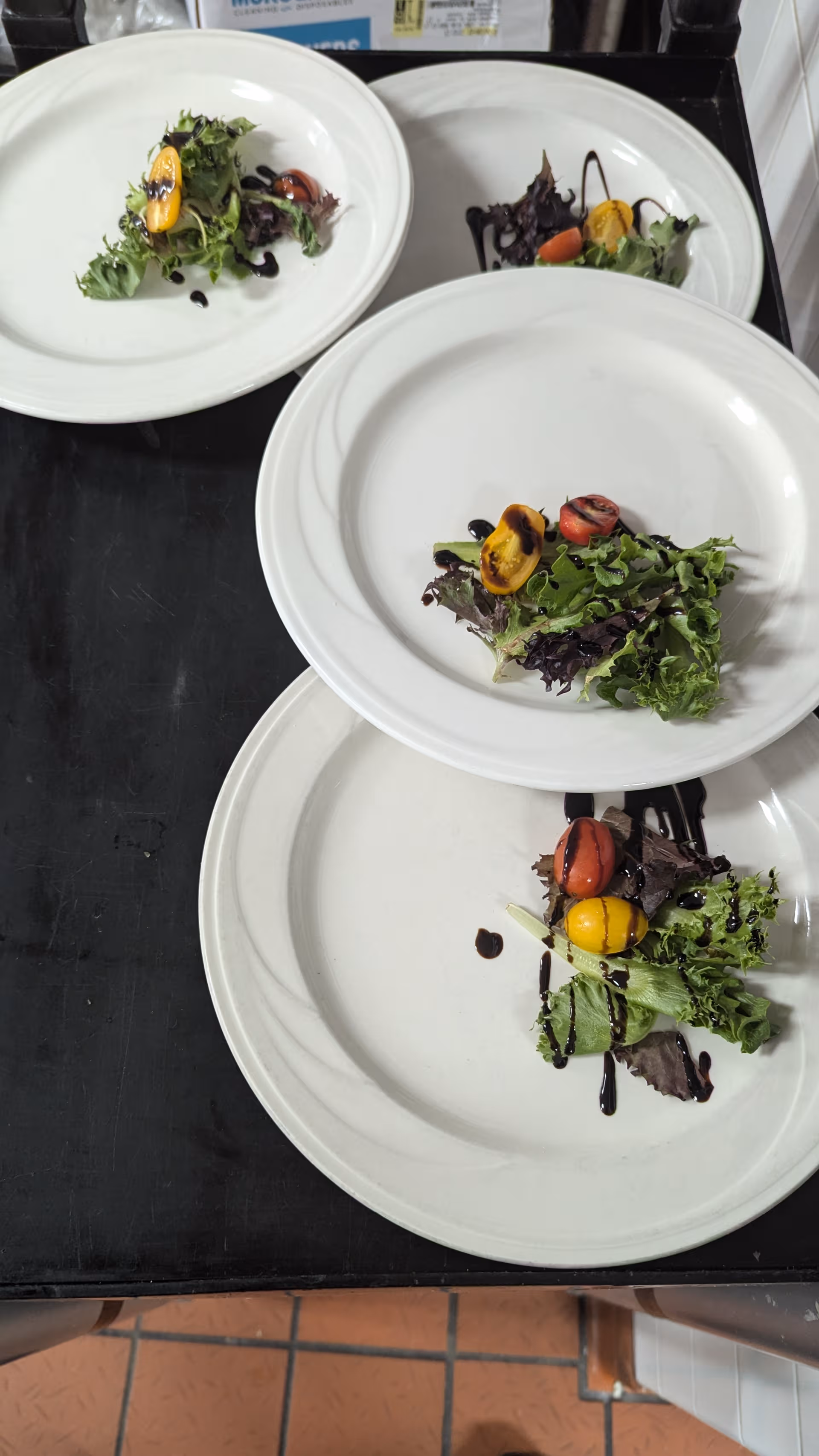 Assorted plated salads on white dishes arranged on a black serving tray.