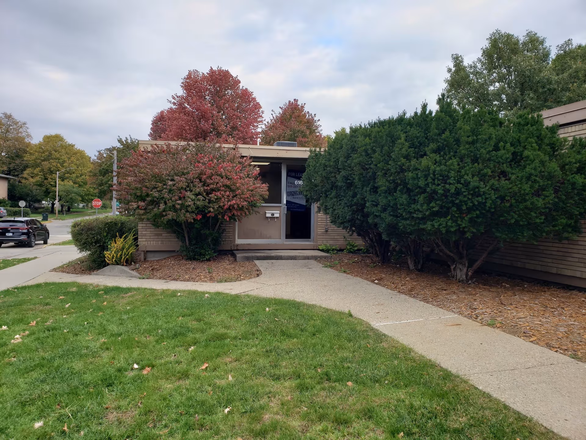 Exterior view of Senior Helpers Central Iowa facility with shrubs, trees, and a sidewalk.