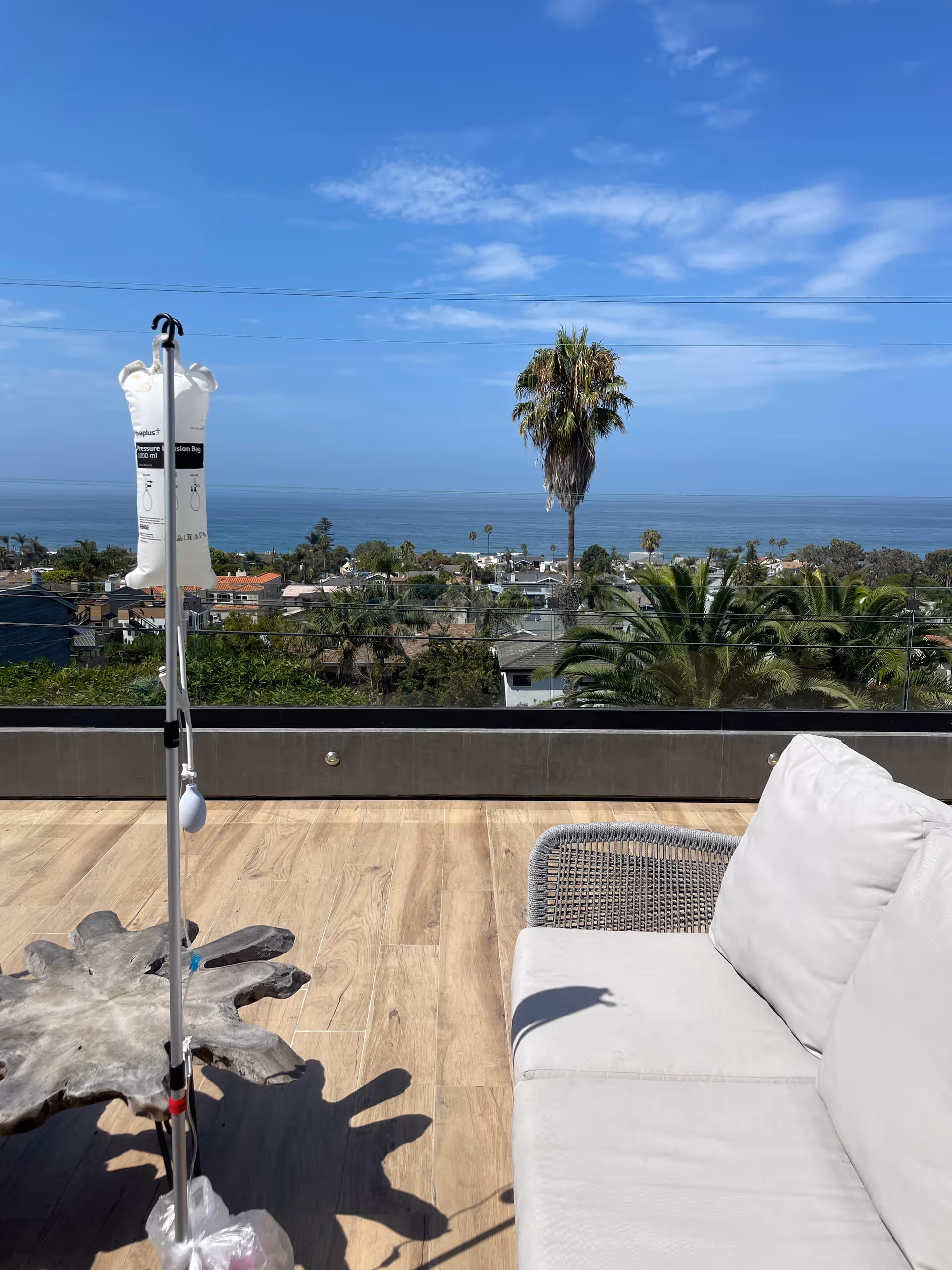 Rooftop outdoor terrace with white sofa, IV stand, and ocean view.