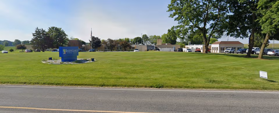 Front view of Regency at Fremont with a green lawn, sign, and parked cars.