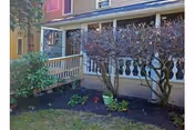 Front exterior of All Seasons Oro Valley with porch, railing, and trimmed shrubs.