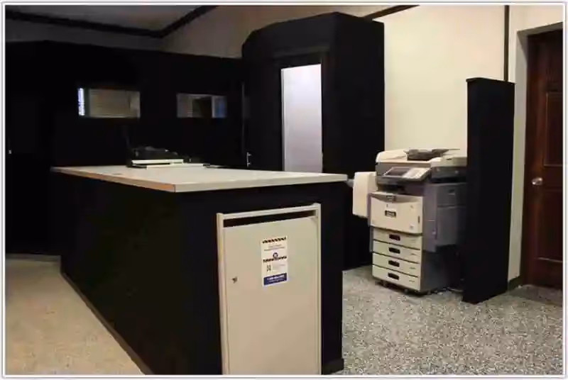 Reception area with a dark wood front desk, copier, and partition walls.