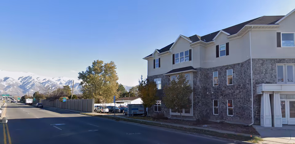 Exterior view of a Visiting Angels Senior Home Care Layton building on a street with mountains.