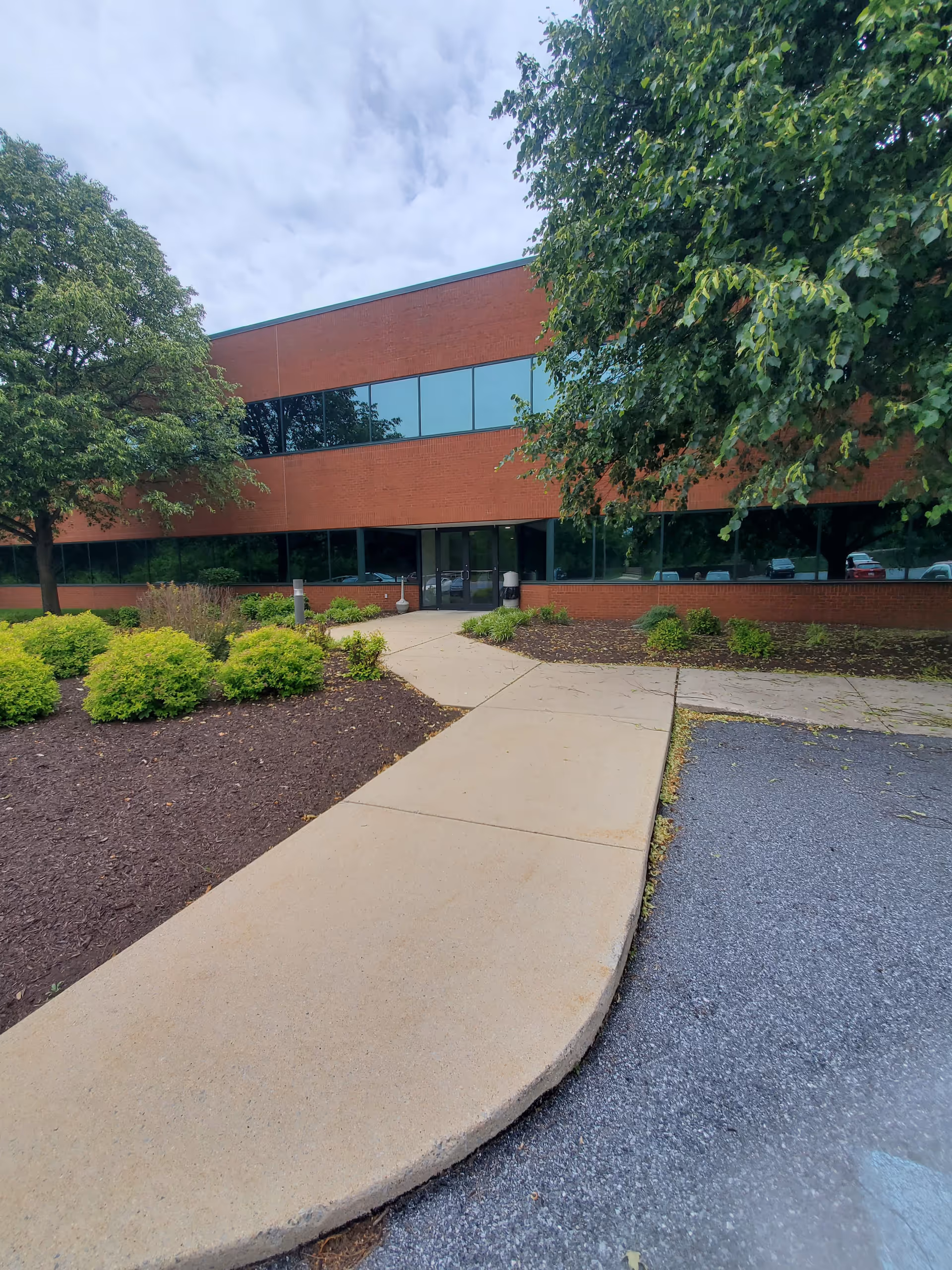 Brick, modern building exterior with glass windows and a curved walkway.