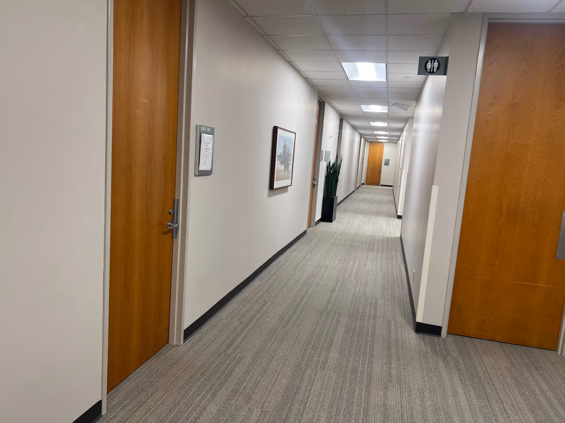 Long, well-lit interior corridor of a senior living facility with closed doors.