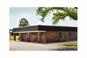 Brick exterior of a single-story senior living facility with an entryway and trees.