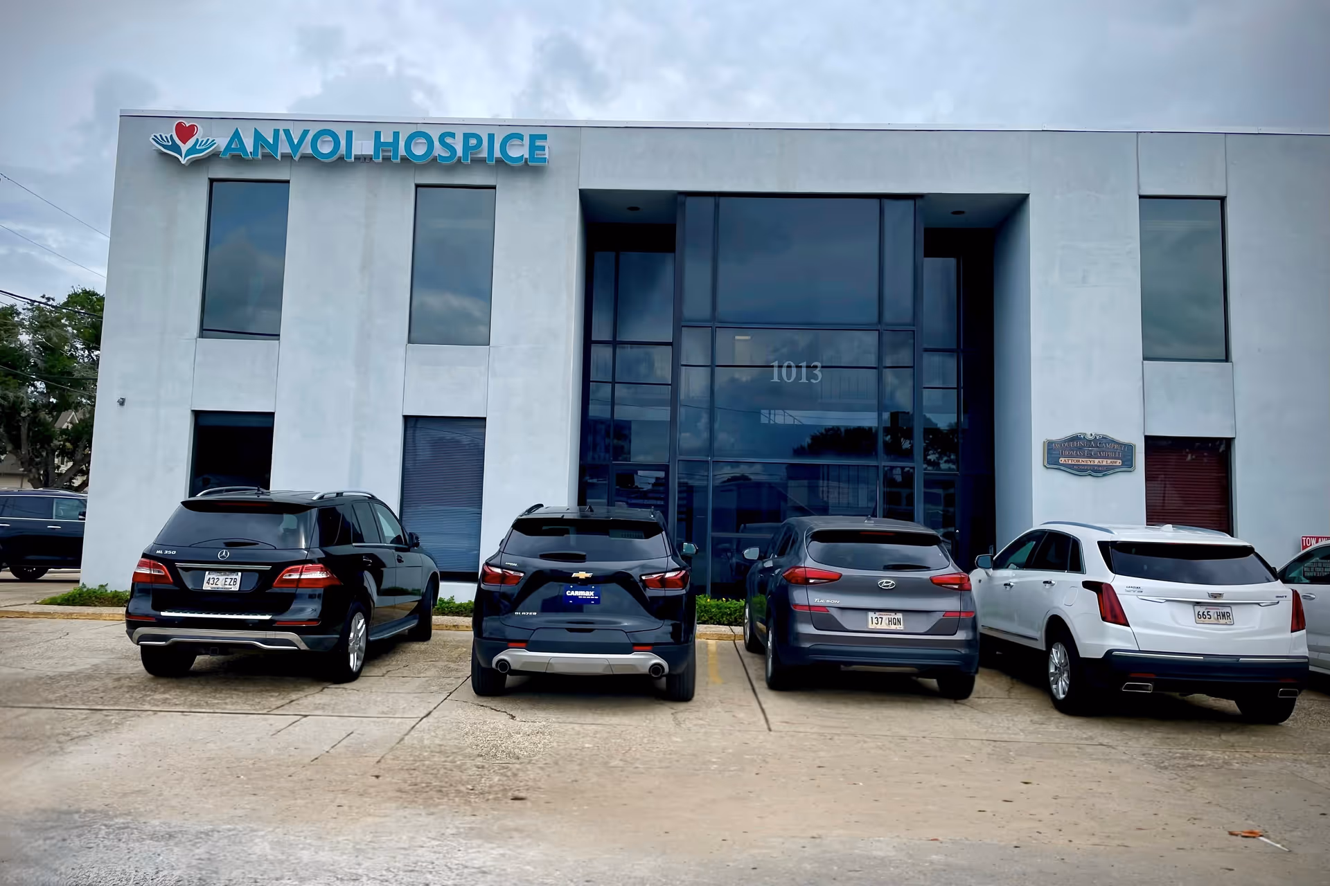 Front view of Anvoi Hospice building with several cars parked outside.