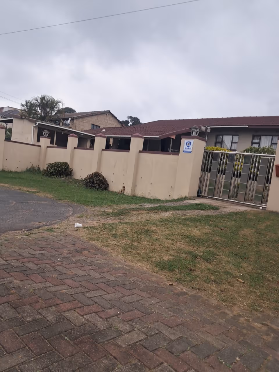 Exterior view of Barker Place facility with beige wall, gate, and driveway.
