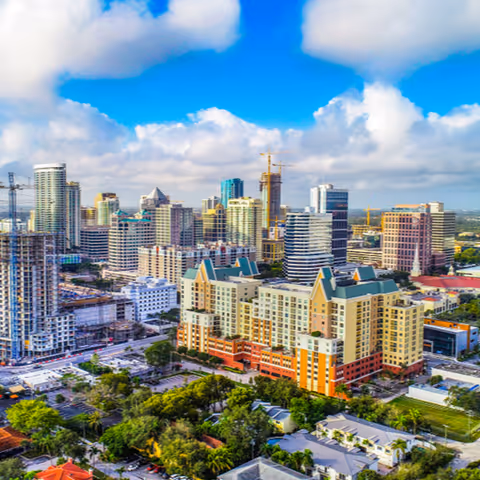 City skyline of high-rise buildings under a bright blue sky.