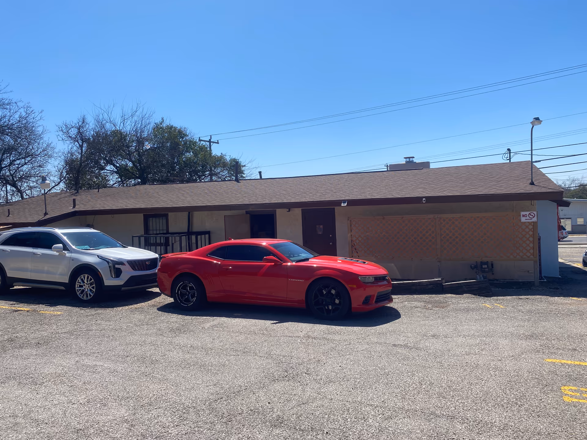 Single-story beige building exterior with two parked cars in a lot.