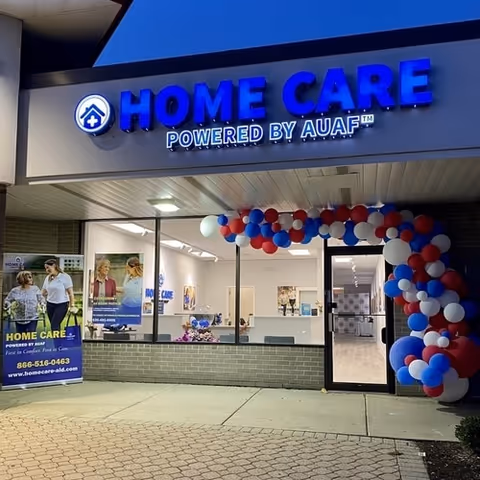 Exterior view of a Home Care Arizona storefront with blue sign and red, white, blue balloons.