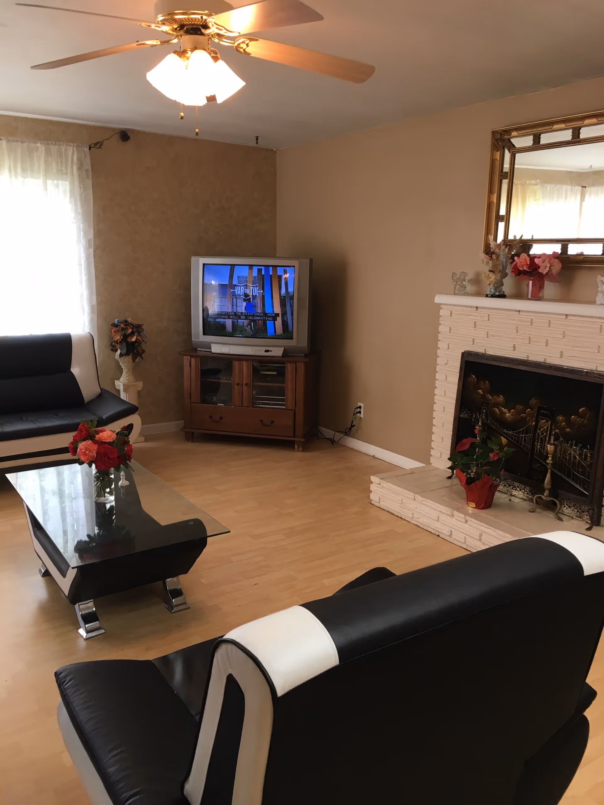 Cozy living room with black-and-white leather seating, glass coffee table, TV, and fireplace.