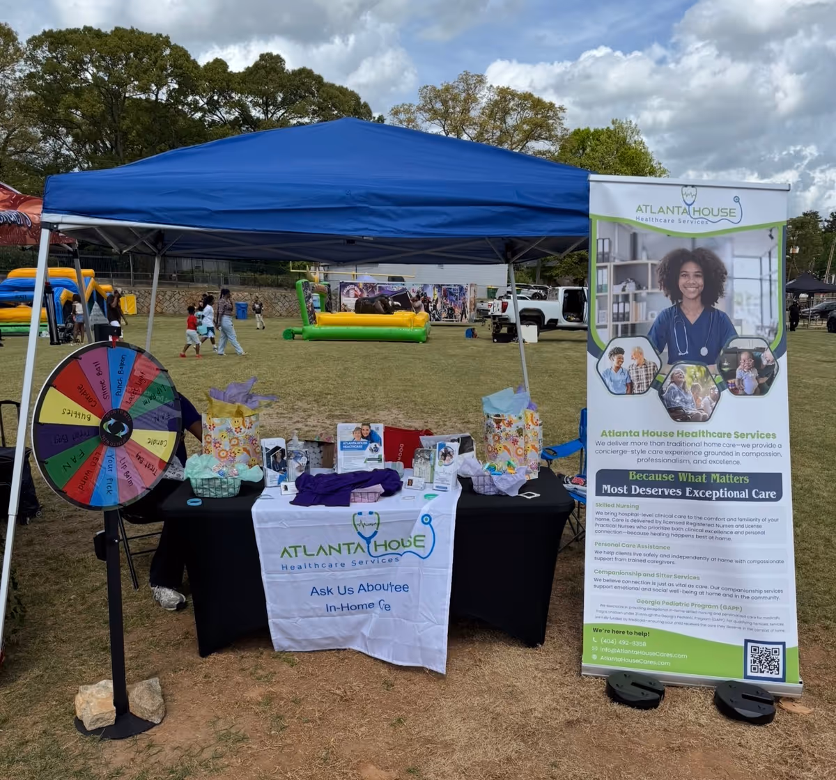 Outdoor booth under a blue canopy promoting Atlanta House Healthcare Services at a community fair.