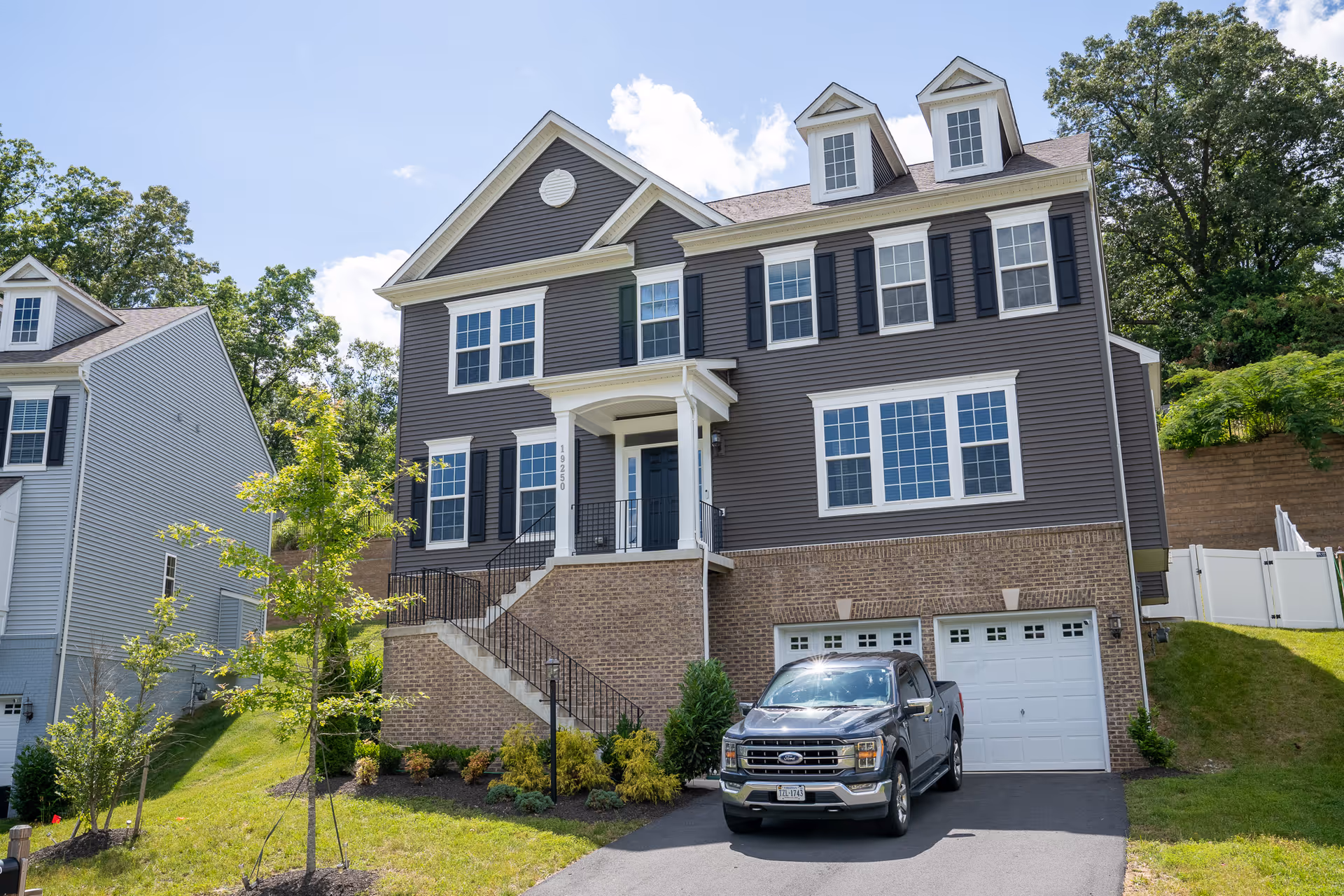 A large brown siding two-story building with brick foundation and a driveway.