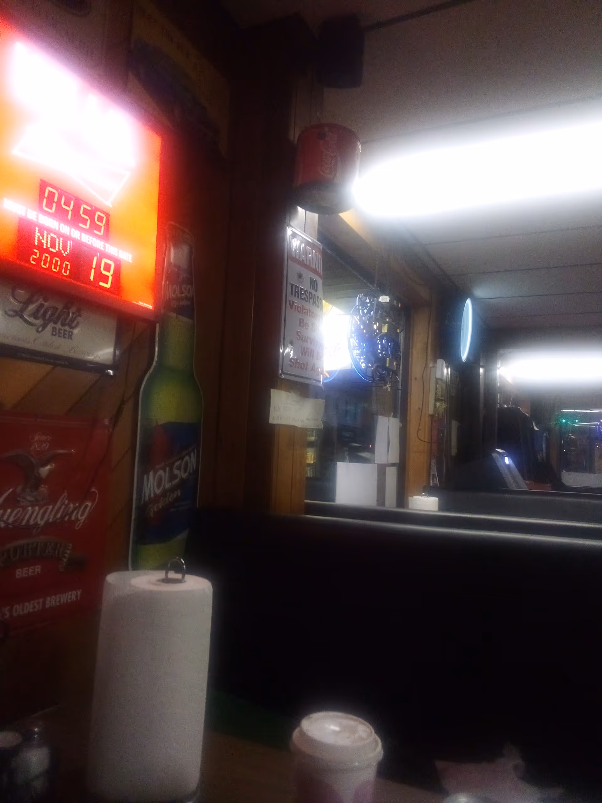 Dimly lit diner interior with booths, neon signs, and beverage advertisements along wooden walls.