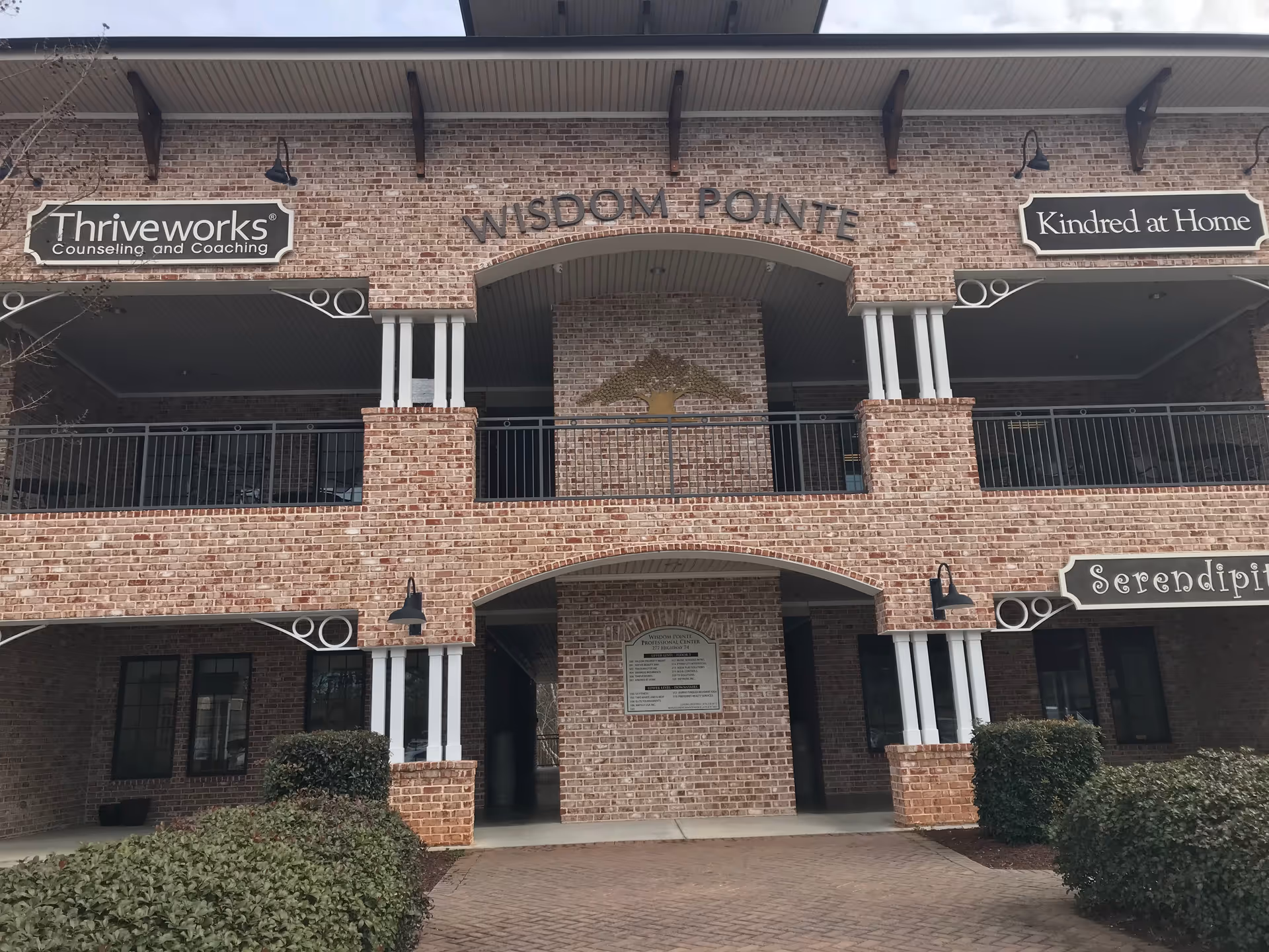Brick building exterior with arches and signs for Wisdom Pointe and partners.