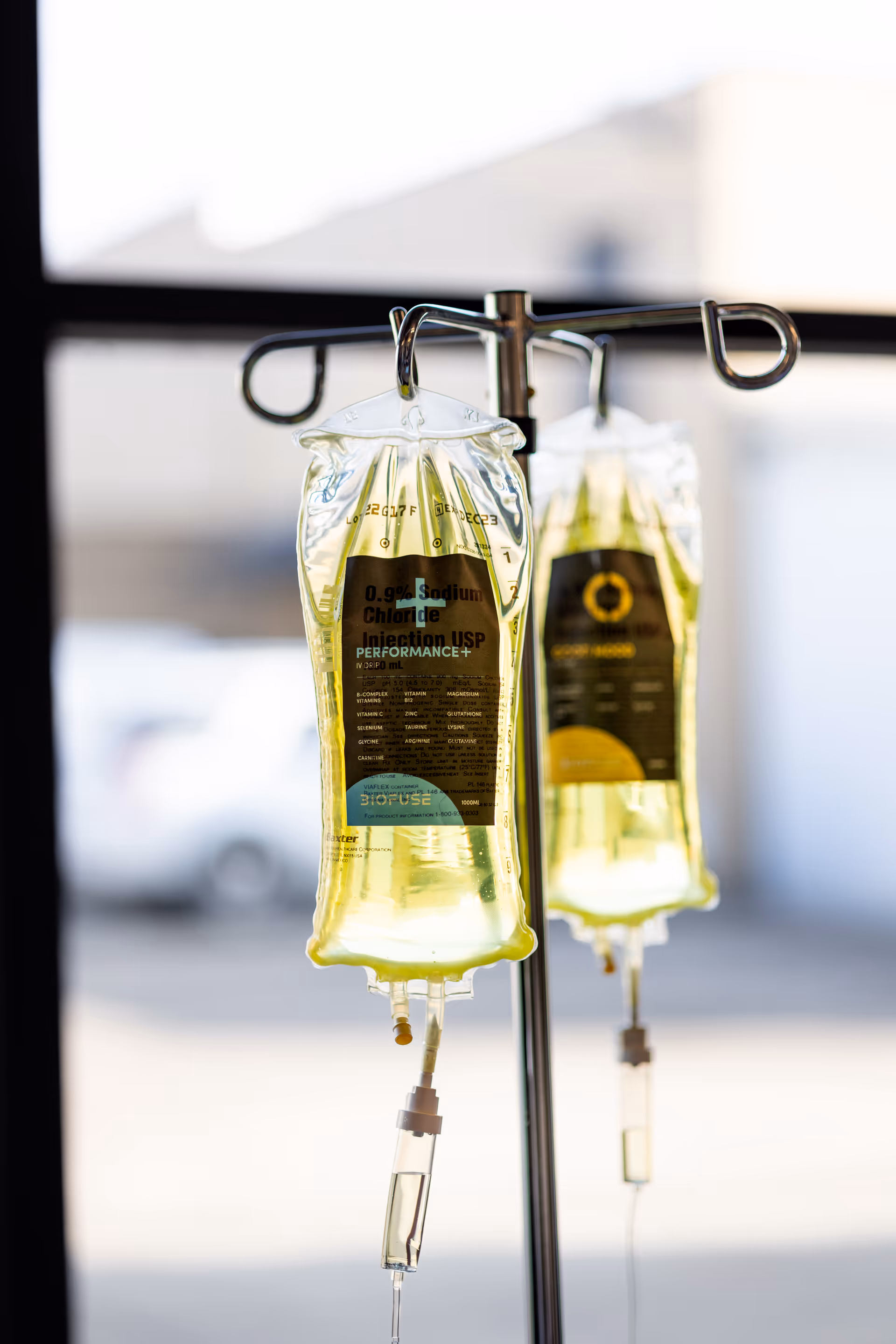Two IV therapy bags hang from a stand inside a medical facility.
