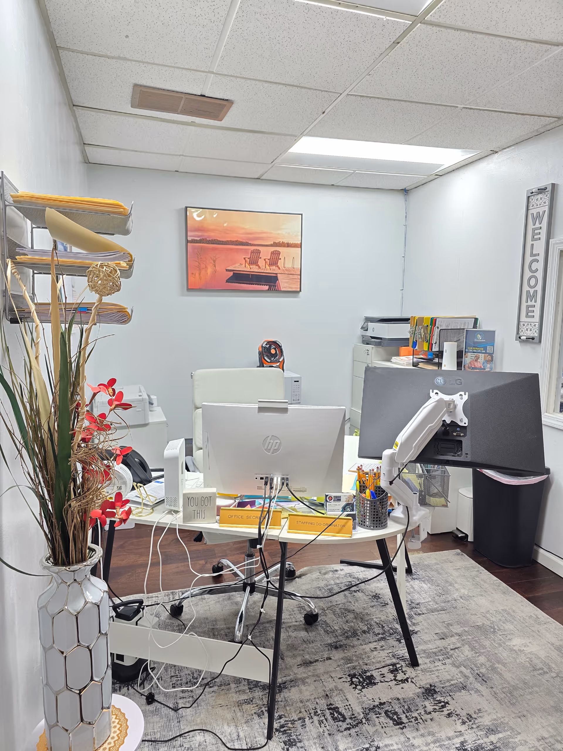 Office workspace with two computer monitors, office supplies, and a welcome sign.