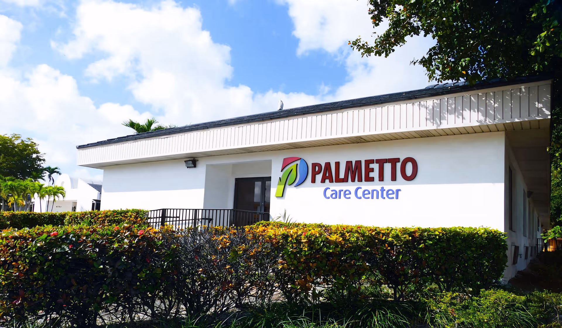 Exterior view of Palmetto Care Center building with hedge and signage.