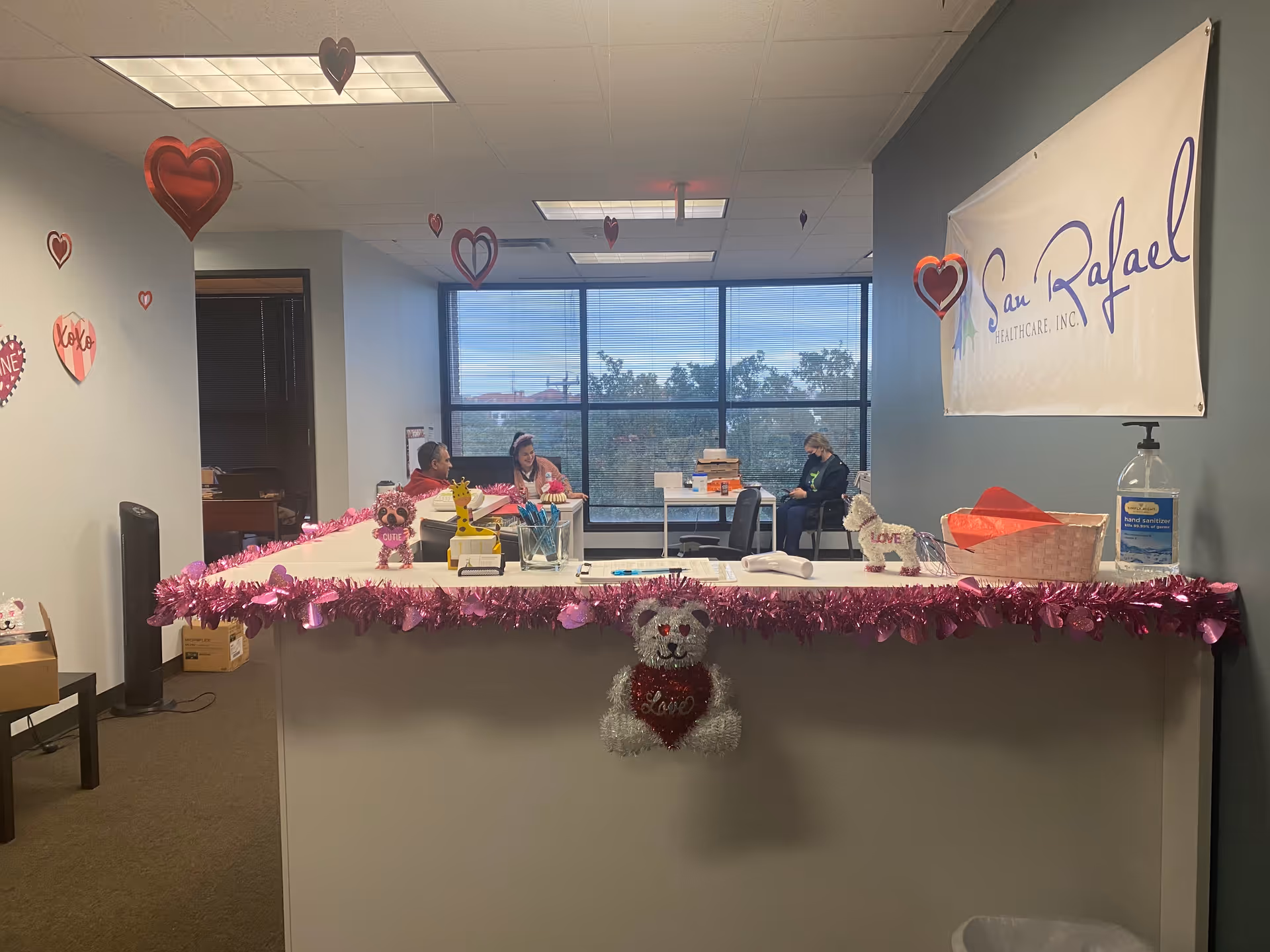 Indoor reception area at San Rafael Healthcare with pink decorations and staff behind desk.