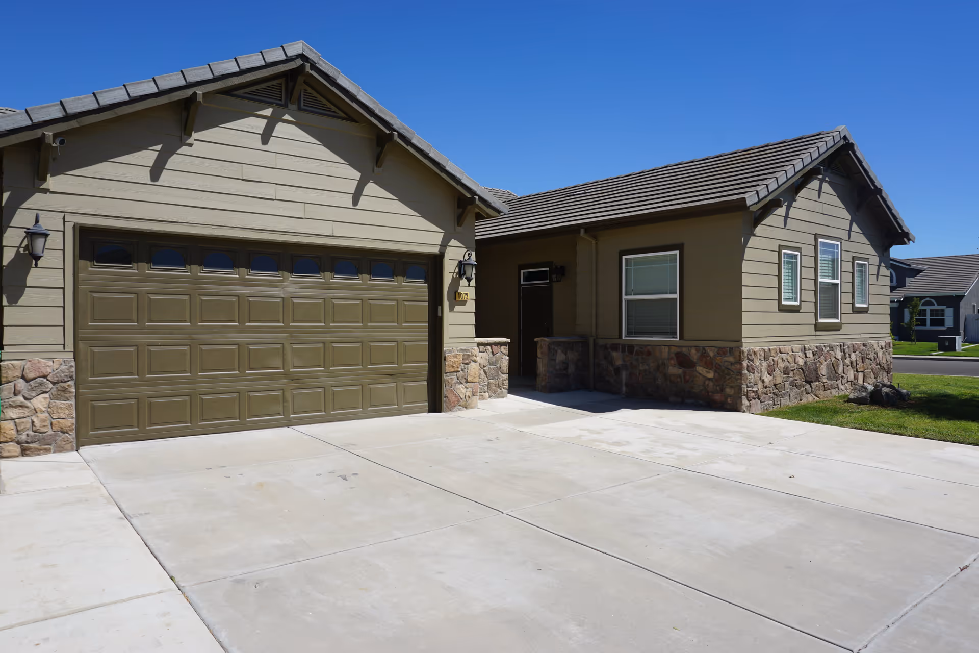 Single-story house-style senior living building with a two-car garage and stone accents.