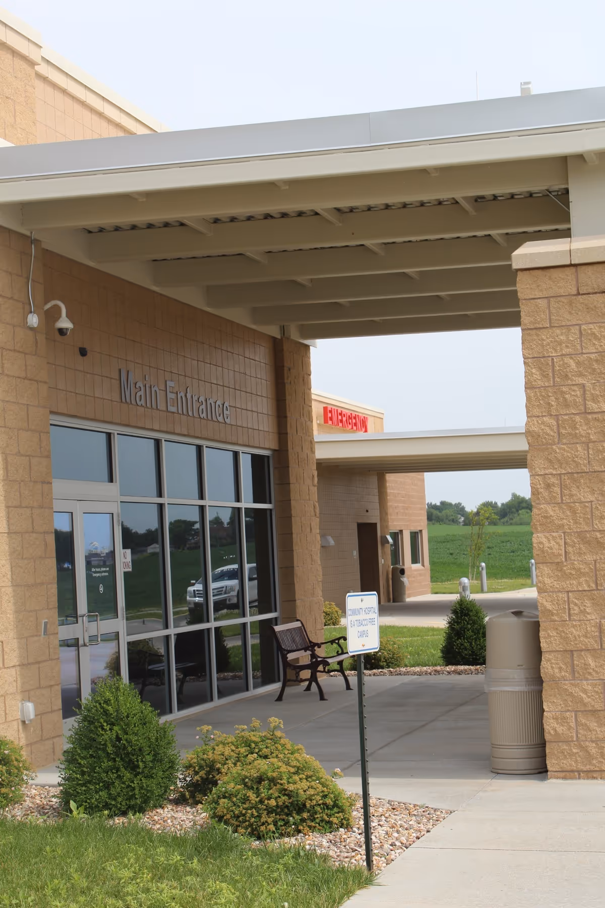 Exterior view of Community Hospital Fairfax main entrance with bench and greenery.