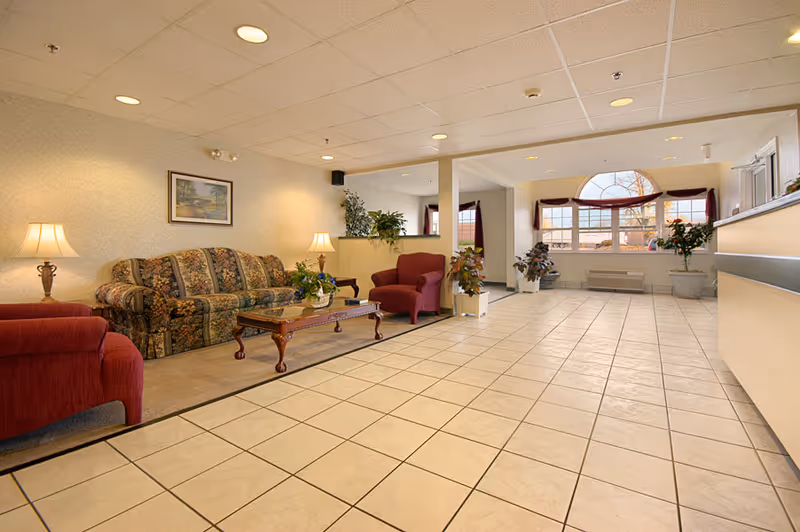 Lobby at Rosemont Senior Living Centre with seating, lamps, plants, and a reception desk.