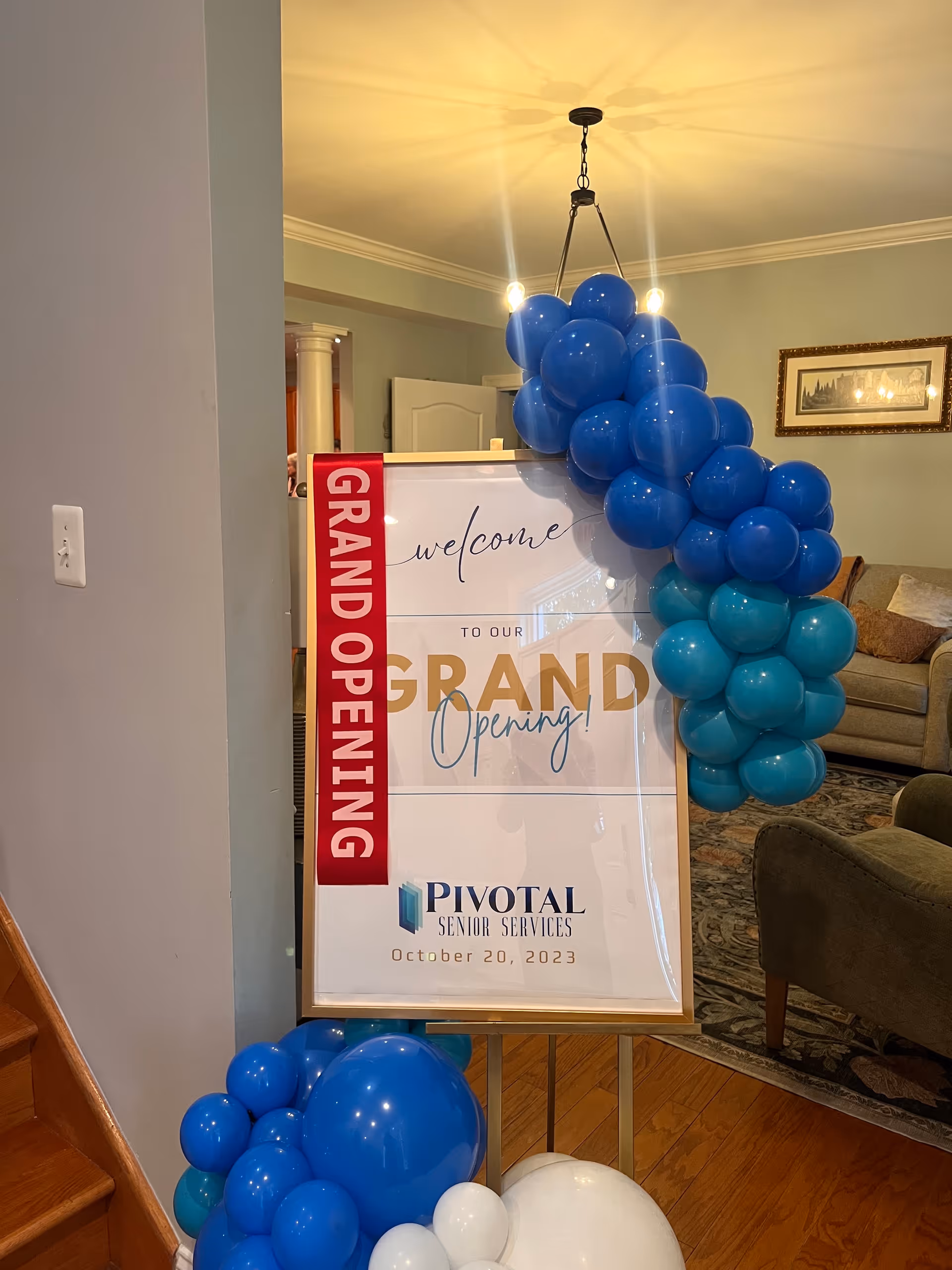 Lobby area with blue balloon arch beside a Grand Opening sign for Pivotal Senior Services.