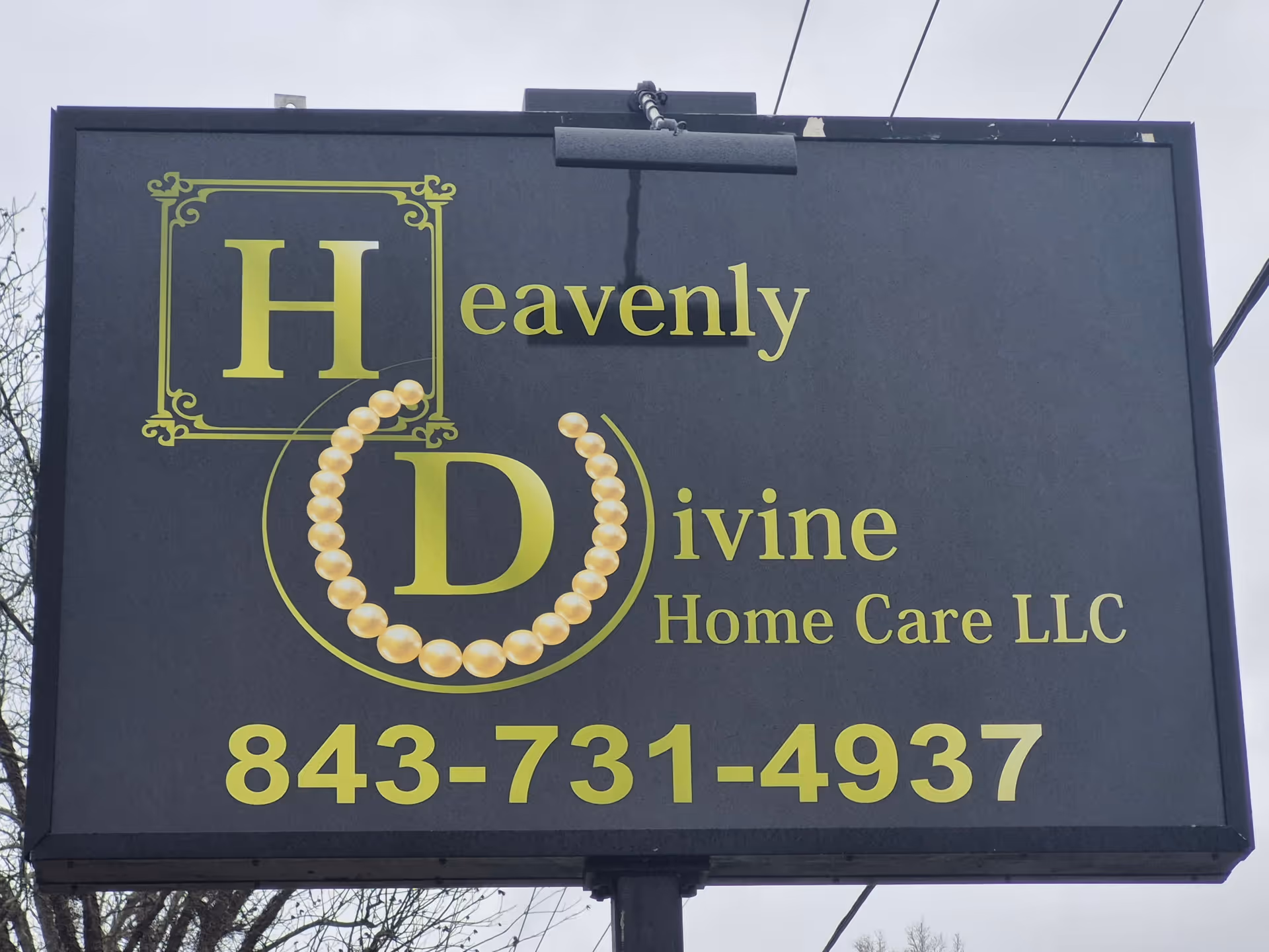Large dark outdoor signboard advertising Heavenly Divine Home Care LLC with a phone number.