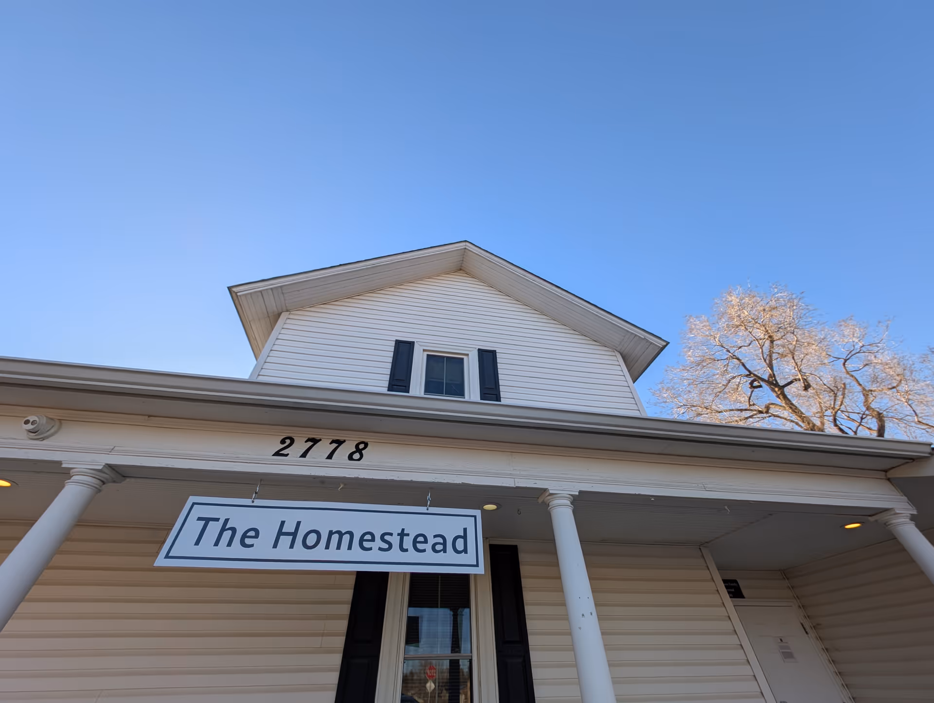 White building with a front porch, sign reading 'The Homestead' and address 27718.