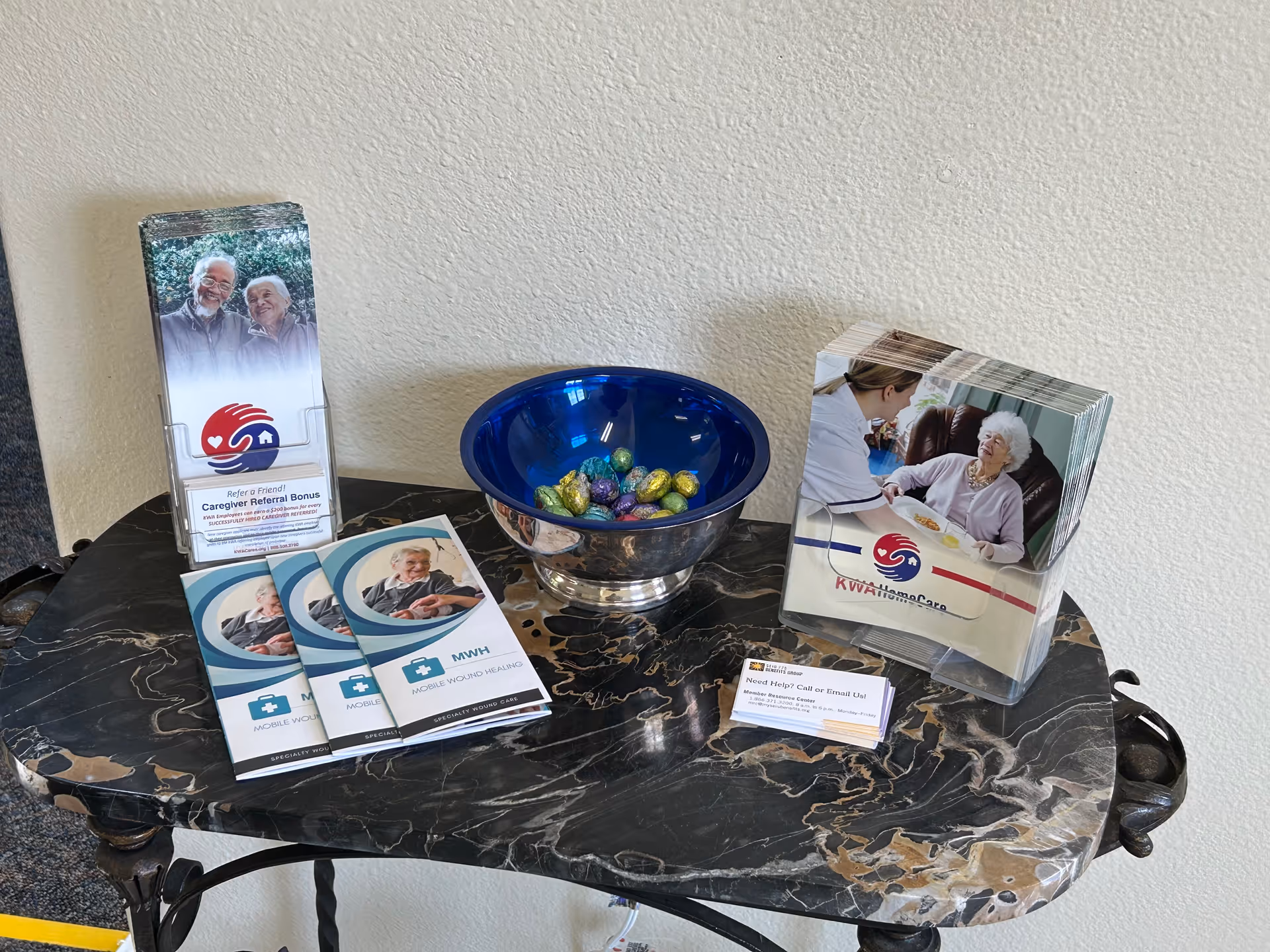 Marble table with brochures, pamphlets, and a blue candy bowl in a lobby display.