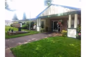 Front view of Americana Health and Rehab Center with a green lawn and inviting entrance.