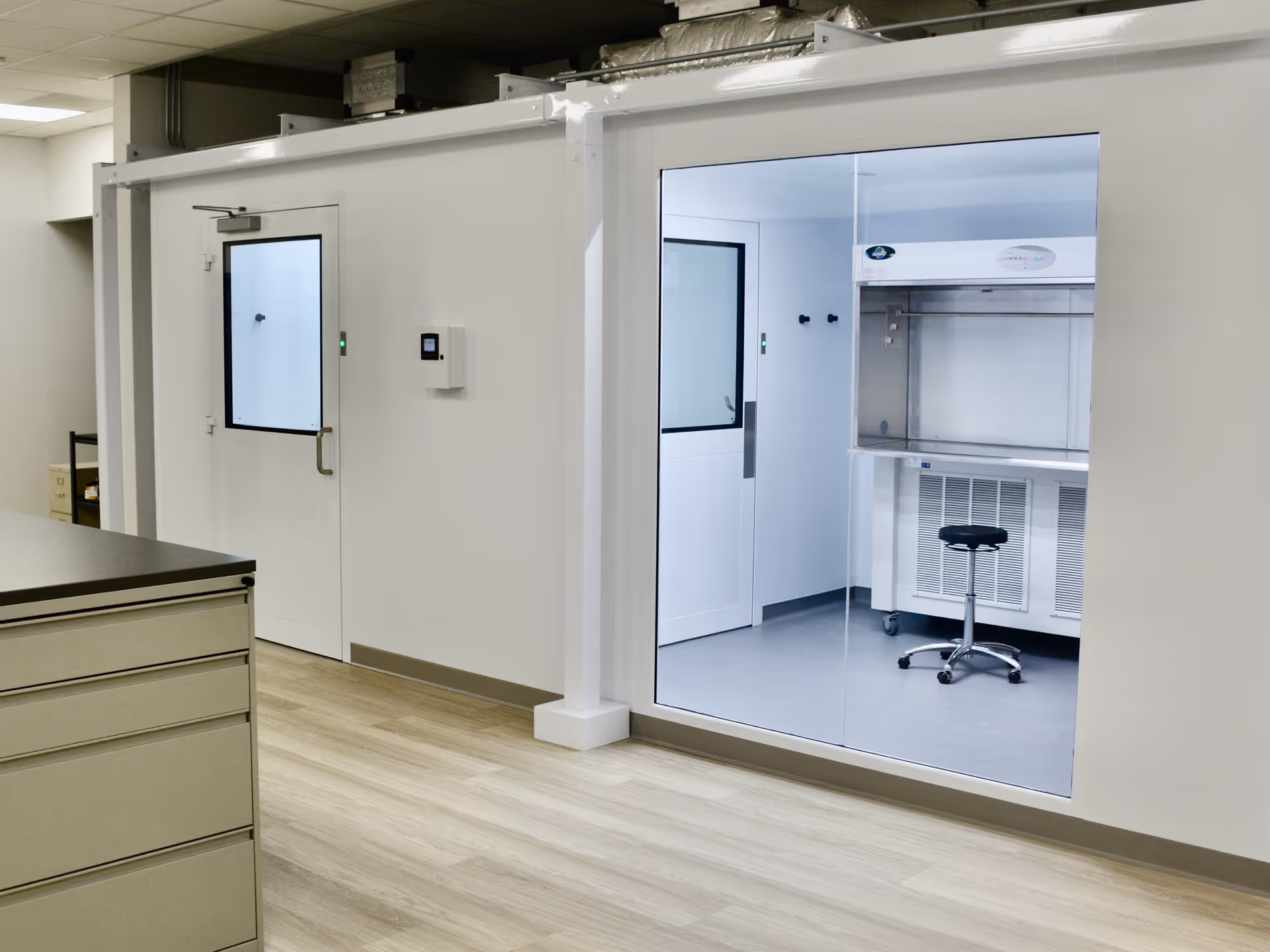 Sterile infusion lab interior with glass-walled room and medical equipment.