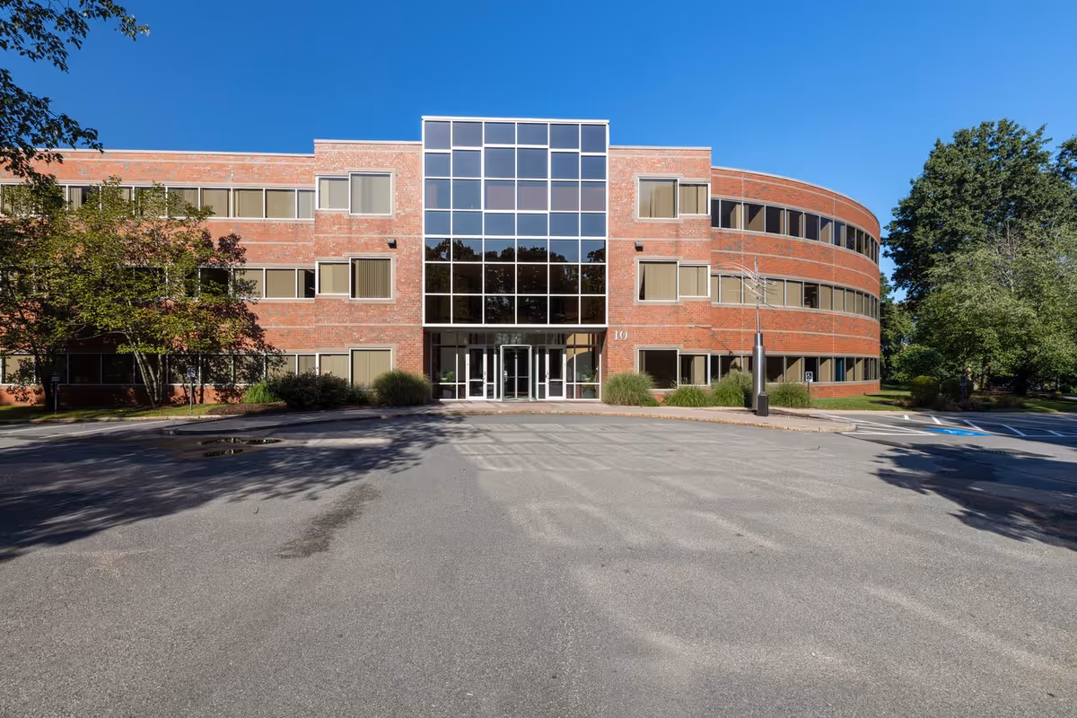 Brick senior living facility exterior with glass entry and parking in front