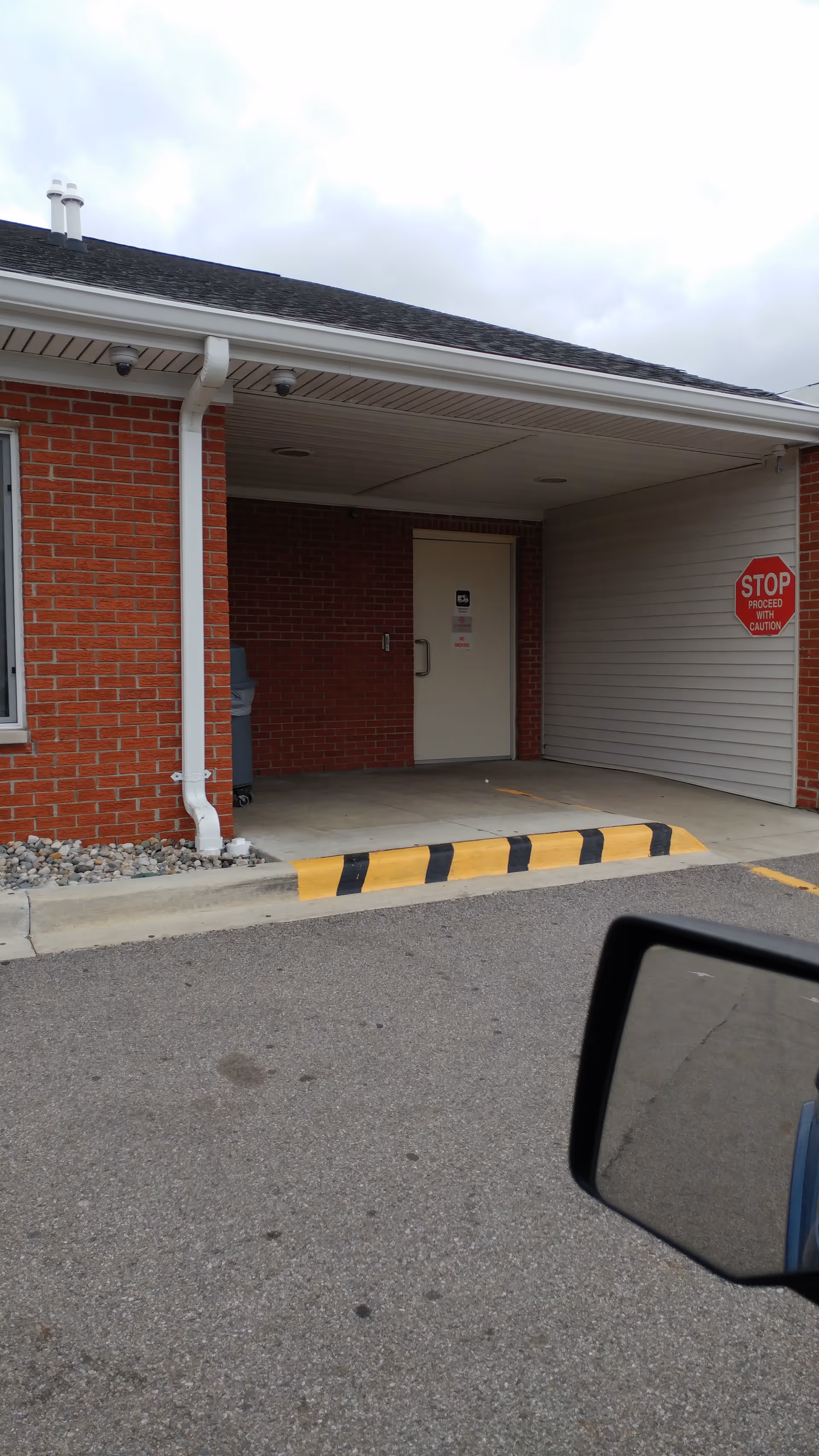 Exterior view of the Medilodge of Taylor entrance with brick wall and stop sign