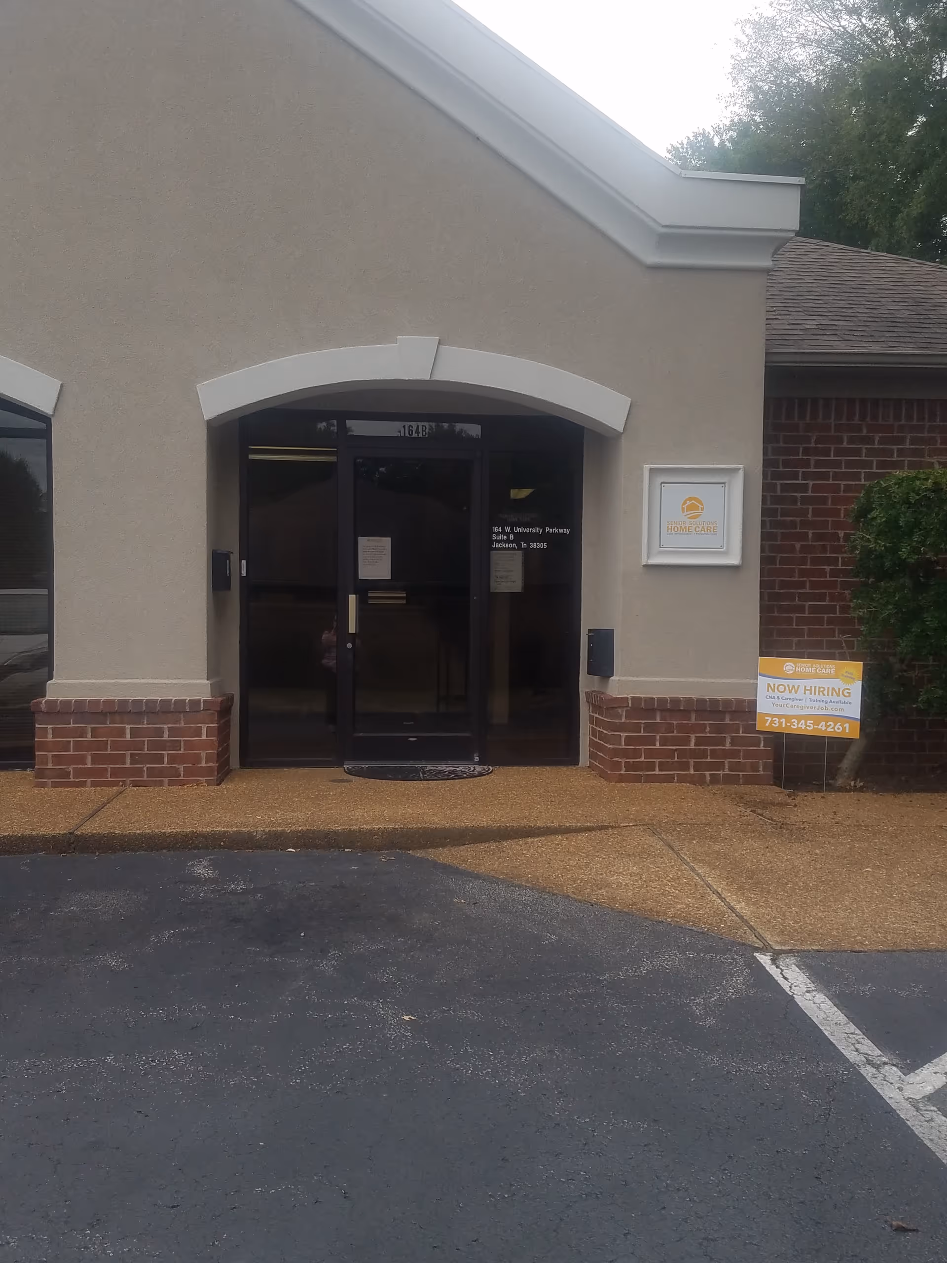 Front entrance to Senior Solutions Home Care facility with glass doors and Now Hiring sign.