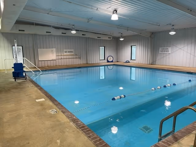 Indoor swimming pool with lane dividers and a blue chair along the edge.