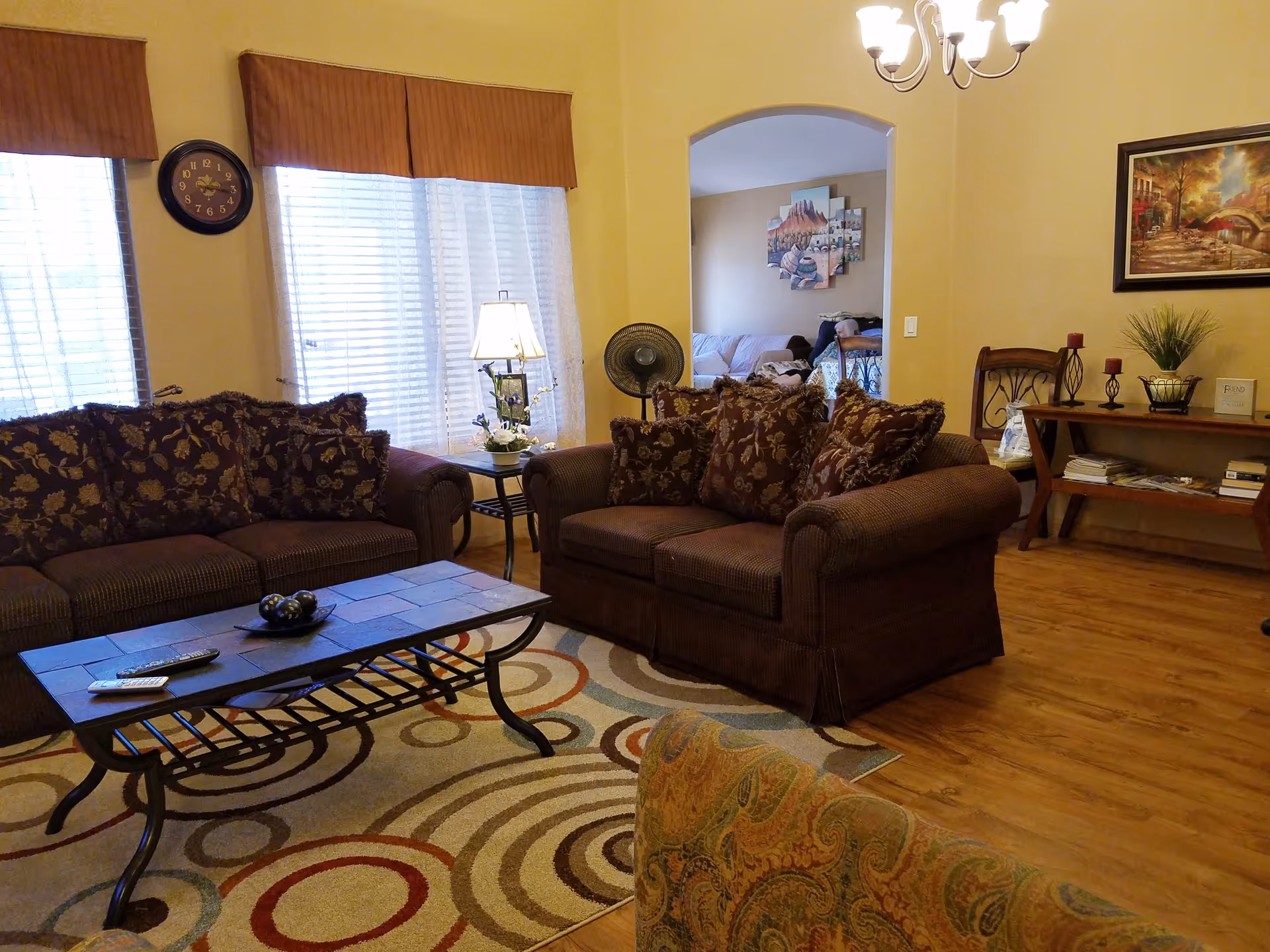 Cozy living room with brown upholstered sofas, coffee table, rug, and decorative wall art.