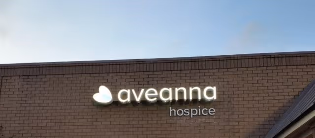 Exterior brick building with Aveanna Hospice sign against blue sky
