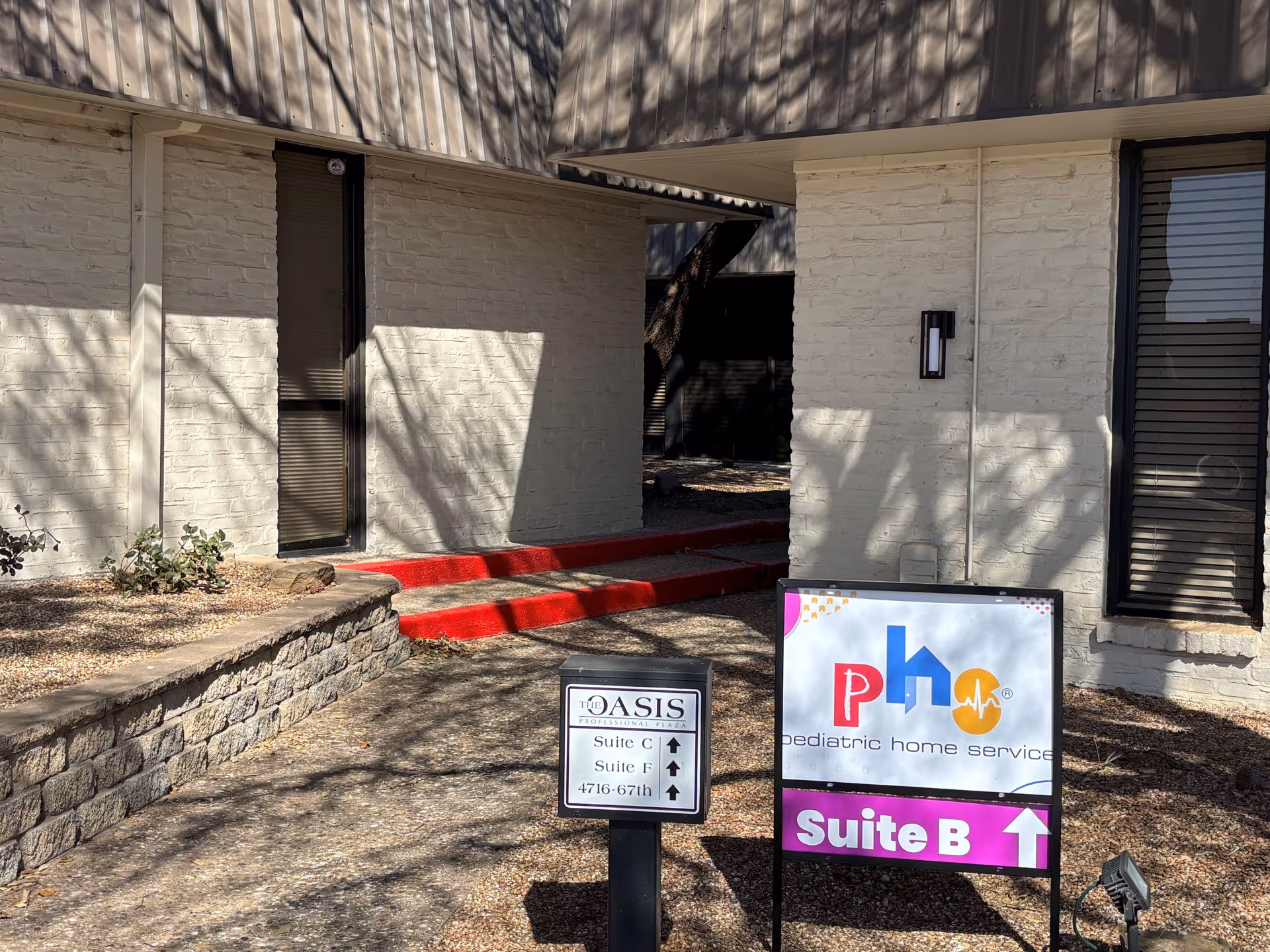 Exterior building entrance with red steps and signs for Pediatric Home Service.