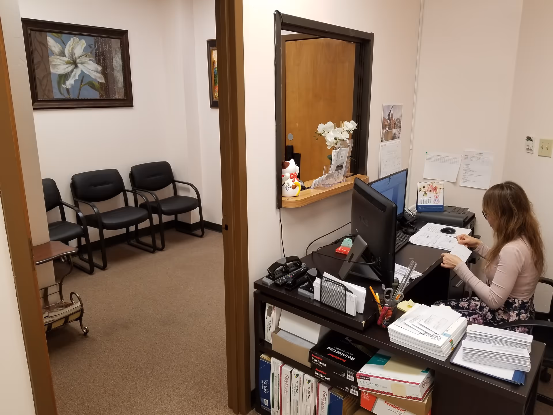Reception area of a senior living facility with a receptionist at a desk and waiting chairs.