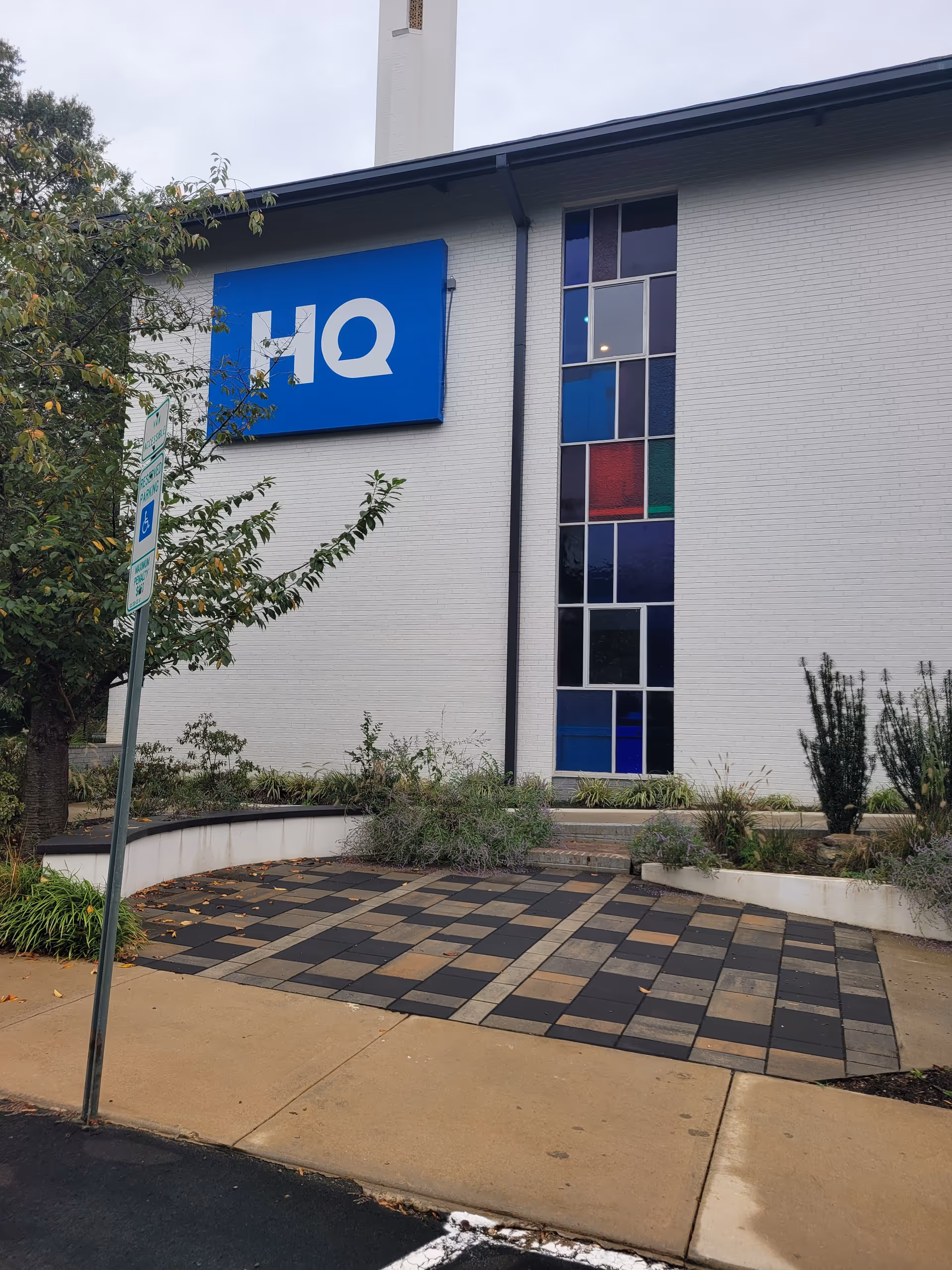 Exterior view of a building with a blue HQ sign and colorful glass windows.