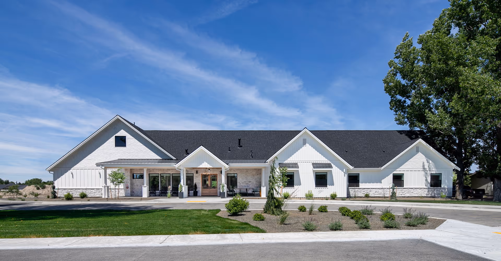 Front exterior view of The Ponderosa Estate: a single-story white building with landscaped entry
