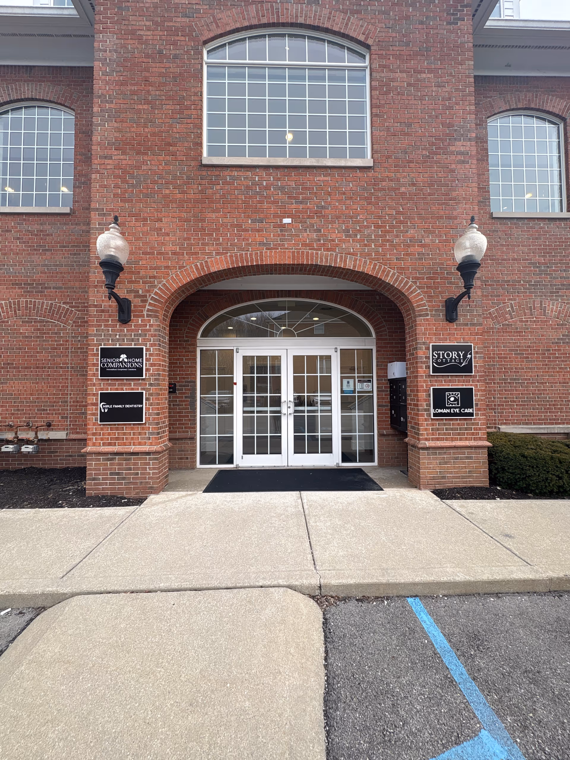 Brick building entrance with glass double doors and Senior Home Companions signs.